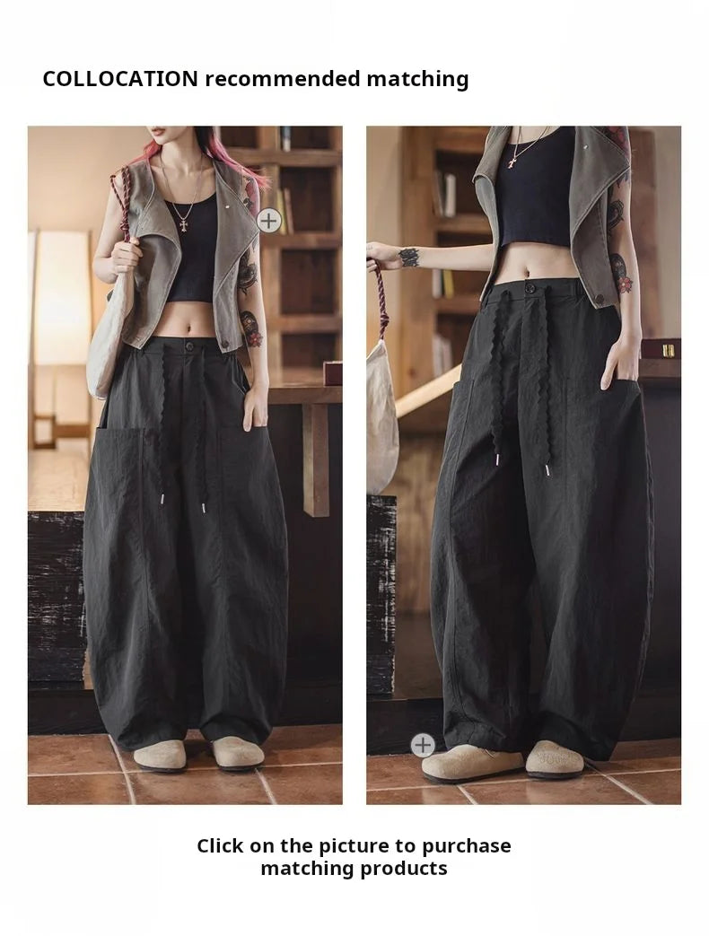 Person wearing a gray jacket, black top, and dark pants in an indoor setting.