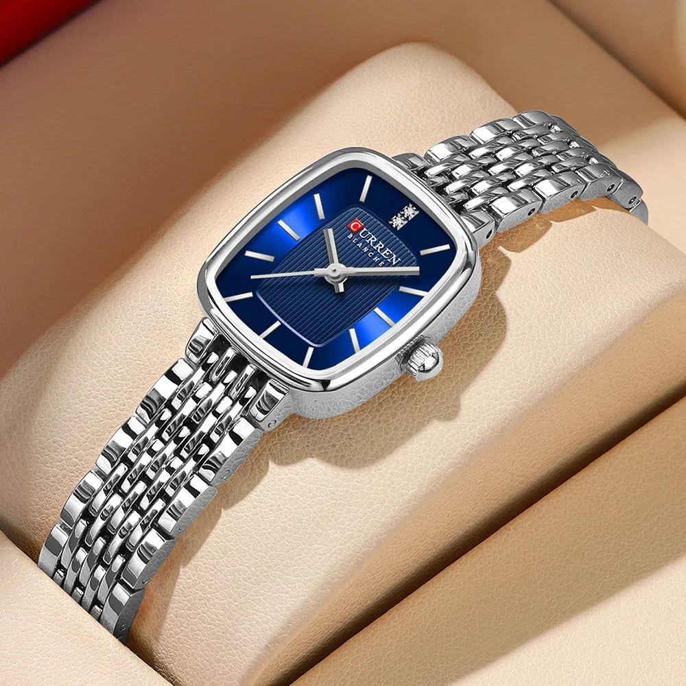 Silver watch with blue face on a beige surface